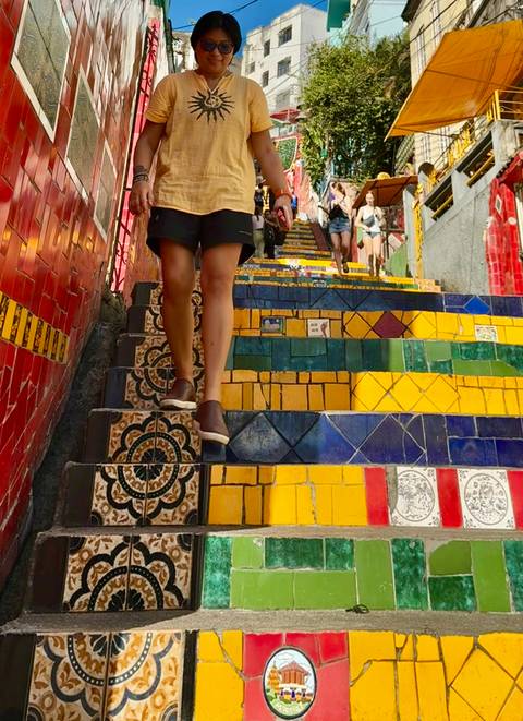       Close view of mosaic-tiled Selarón Steps with a person walking down brightly colored stairs.
  