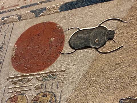       Detailed relief of a scarab and sun disc painted on ancient Egyptian wall carving
  