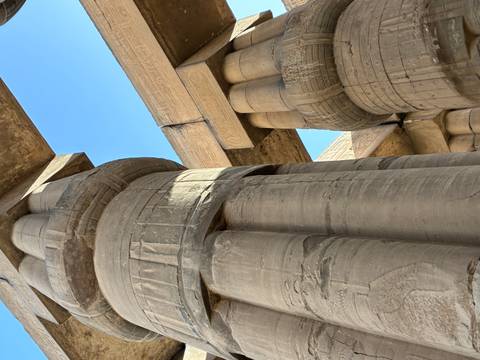       Low-angle view of massive papyrus-shaped sandstone columns with hieroglyphs at Karnak Temple
  