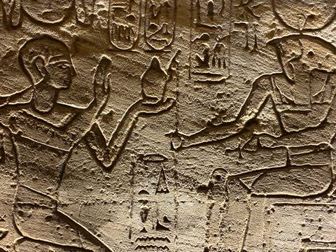      Close-up of deeply carved ancient Egyptian relief depicting figures offering vessels
  