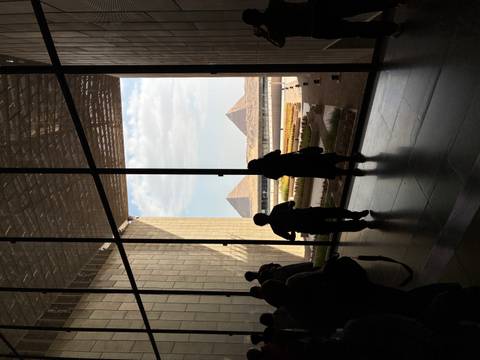       Museum visitors framed in silhouette look out huge glass wall at Giza pyramids in distance
  
