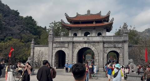       Crowds explore an ornate stone gate of an ancient Vietnamese temple complex.
  