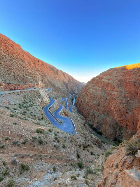       A dramatic serpentine road winds through the steep red cliffs of Todra Gorge.
  