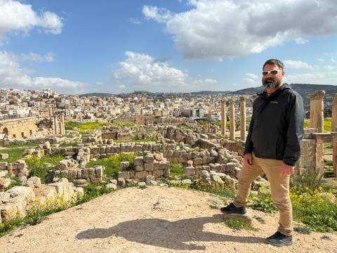       Traveller overlooking extensive Roman ruins and modern Jerash beyond
  