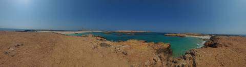       Rocky Omani coastline with turquoise water under a cloudless sky
  