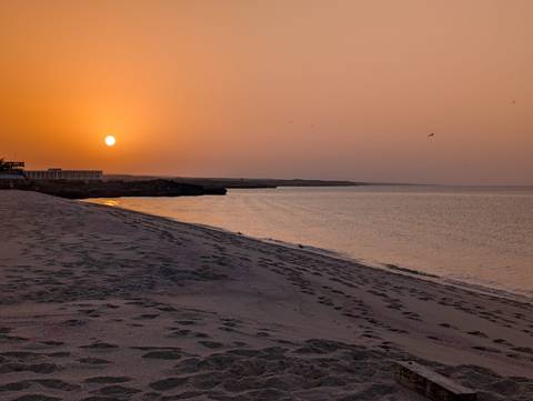       Serene sunset over a quiet sandy beach with warm orange sky
  