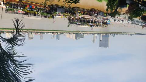       Panoramic view across a wide river toward Phnom Penh’s modern skyline with floating restaurants and boats along the waterfront.
  