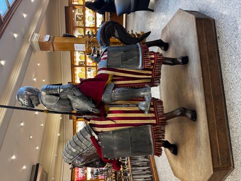       Full-size armored knight on a caparisoned horse displayed inside a brightly lit Spanish souvenir shop.
  