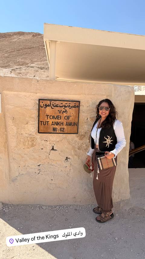       Traveler posing beside the stone sign for Tomb of Tut Ankh Amun No. 62.
  
