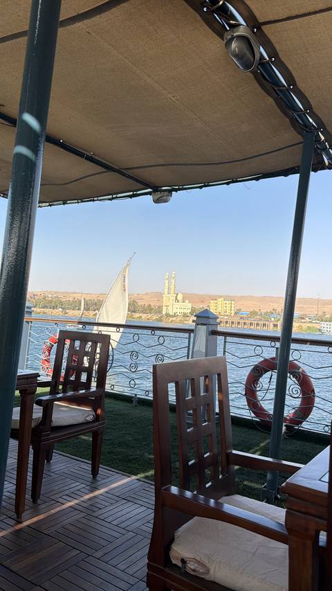       View from a riverboat of a felucca sail and riverside mosque on the Nile.
  