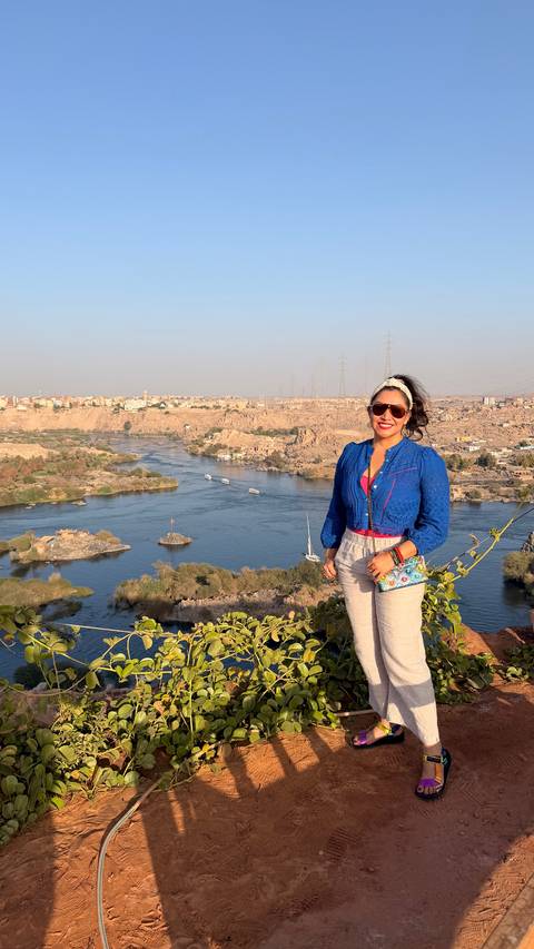      Woman posing at high overlook of the Nile River with islands and boats below.
  