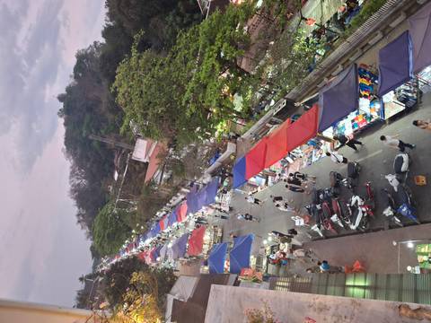       Elevated view of a bustling night market street lined with colorful tents.
  