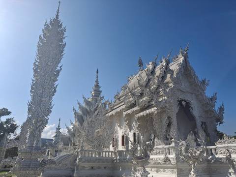       Ornately carved white temple gleaming against a deep blue sky.
  