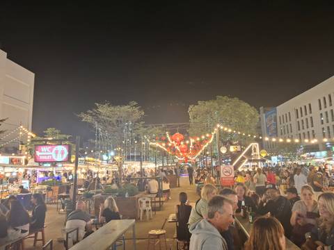      Lively night food market crowded with diners under strings of lights.
  