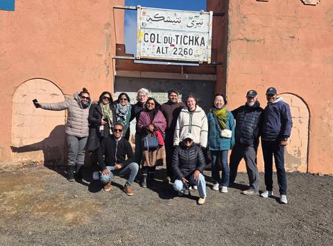       Ten travellers bundle up for a group shot beneath the high-altitude Col du Tichka 2,260 m road sign.
  