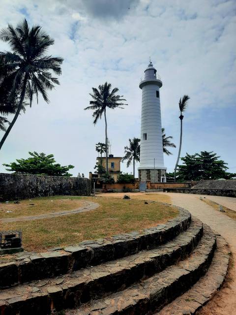      White lighthouse and swaying palms rise above old stone fort walls on Sri Lanka’s coast
  