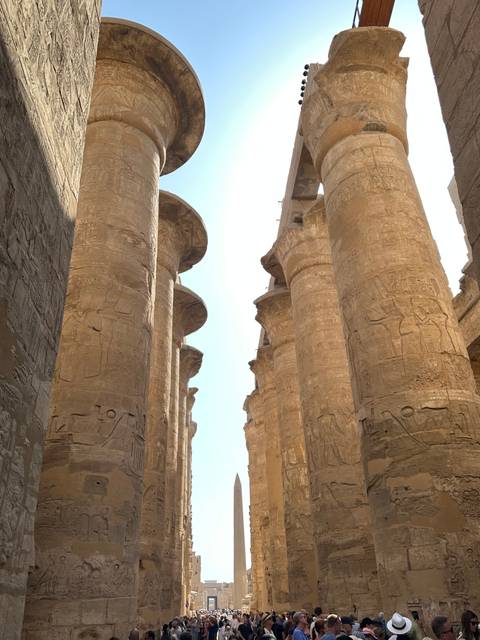       Massive sandstone columns covered in hieroglyphs at Karnak Temple reaching toward the sky
  
