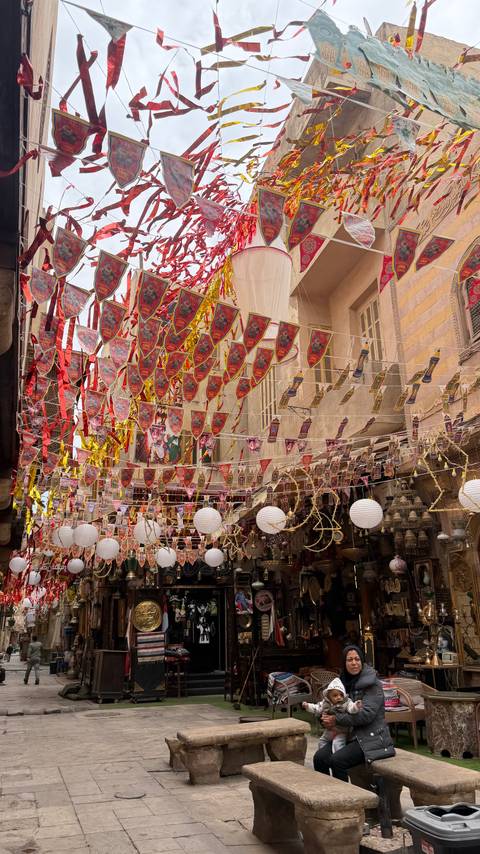       Cairo bazaar alley adorned with colorful pennants and paper lanterns
  