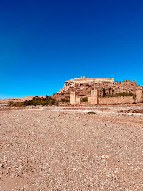       Historic fortified ksar of Ait Benhaddou rising above a dry rocky plain.
  