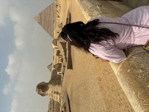       Woman gazing at the Sphinx and pyramids from a stone terrace on a hazy afternoon
  
