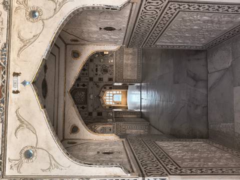       Long marble corridor with intricate inlay work and repeating arches inside a Mughal fort.
  