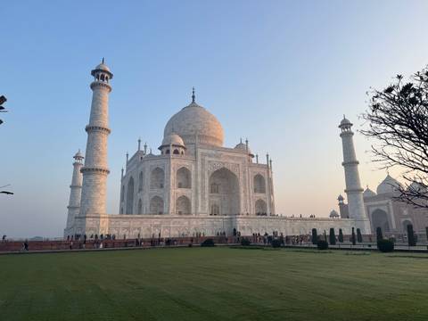       Side perspective of the gleaming white marble Taj Mahal at dawn with soft pastel sky.
  