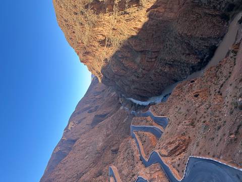       Winding mountain road and river cutting through the steep rocky walls of Todra Gorge.
  