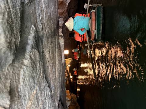       Rowboats paddle through a low cave tunnel in Trang An with reflections on the green water.
  