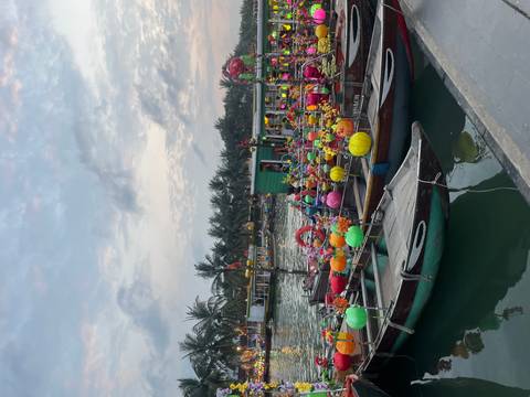       Colorful lantern-decked boats float on Hoi An river in soft evening light.
  
