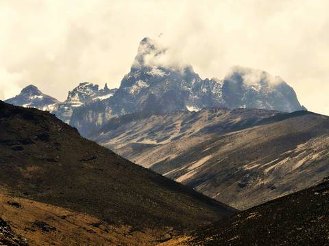       Majestic snow-capped peaks of Mount Kenya rise above rugged volcanic slopes.
  