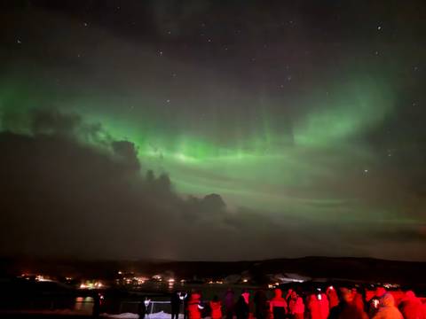       Soft green glow of aurora illuminating clouds in the Arctic night sky.
  