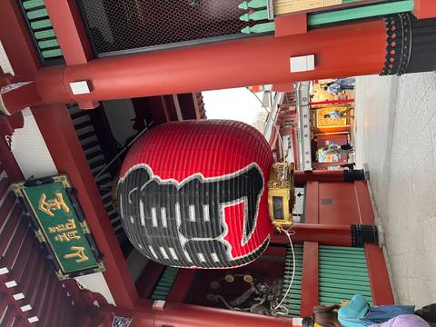       Massive red paper lantern hangs beneath the Kaminarimon gate at Senso-ji temple.
  