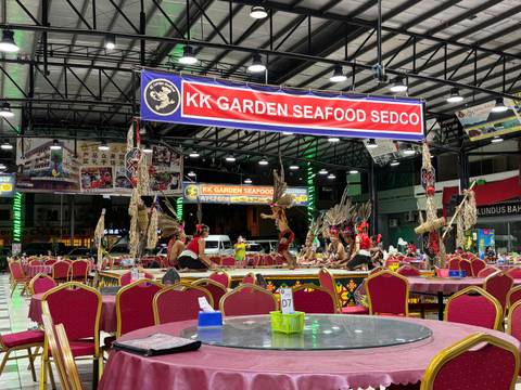       Lively KK Garden Seafood hall with cultural dancers performing between red-clothed tables.
  