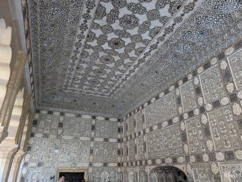       Dazzling mirrored ceiling and walls of Sheesh Mahal reflect patterned light in Amber Fort.
  