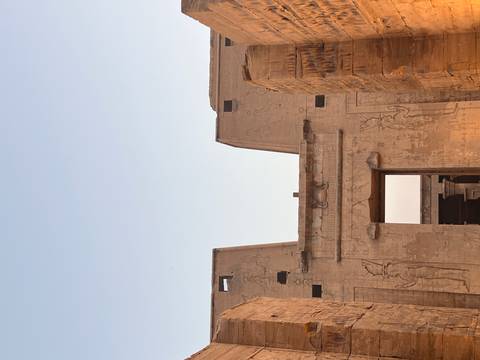      Ancient sandstone temple pylon adorned with carvings set against a pastel dusk sky.
  
