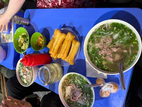       Duplicate pho and street-food spread on blue table.
  