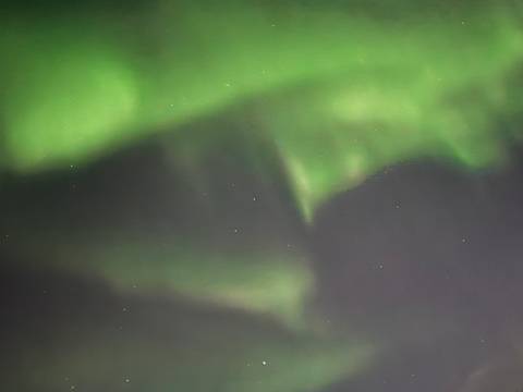       Blurred bands of green aurora and faint stars create an abstract night-sky scene.
  