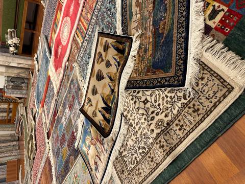       Rows of colourful Turkish carpets laid out in a showroom for display.
  