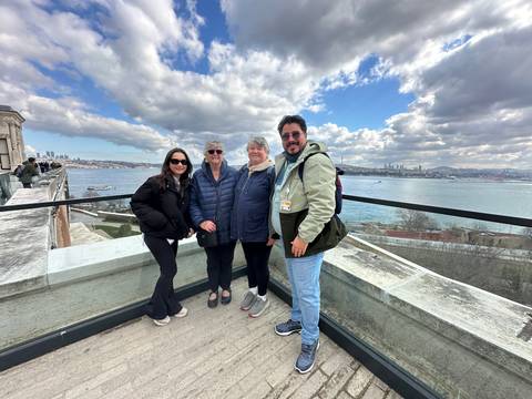       Group of travellers pose on a terrace overlooking the Bosphorus and Istanbul skyline.
  