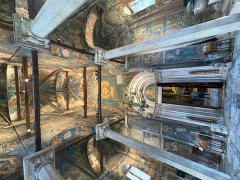       Richly frescoed interior of a historic monastery with marble columns and arched doorway.
  