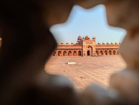       Wide courtyard of Fatehpur Sikri framed artistically between carved sandstone lattices.
  