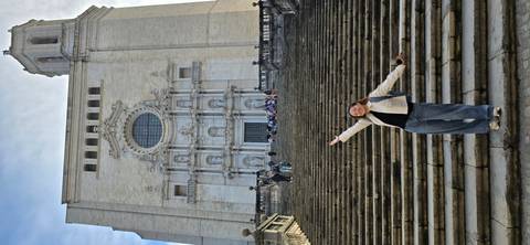       Young traveler posing on the grand staircase leading up to Girona Cathedral’s ornate façade.
  