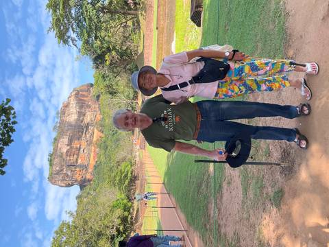       Couple standing on a path with the towering Sigiriya Lion Rock in the background.
  