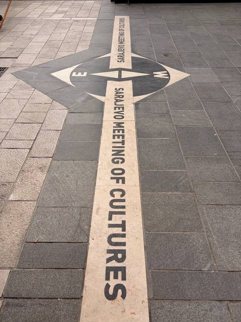       Pavement inscription marking the Sarajevo Meeting of Cultures line on city streets.
  
