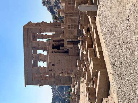       Stone ruins and columns of the Temple of Philae under a bright blue Egyptian sky.
  