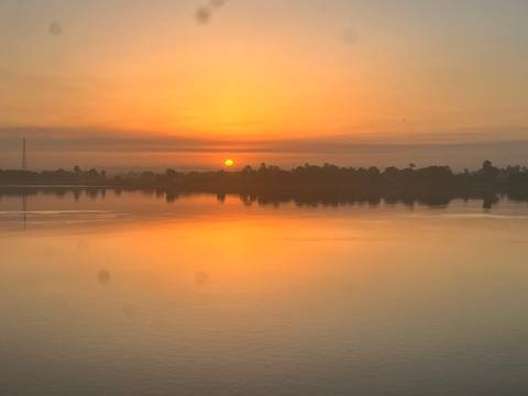       Serene sunset casting orange hues across a calm river reflecting the glowing sky.
  