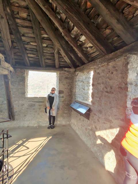       Woman standing inside a stone castle room with sunlight coming through square windows
  