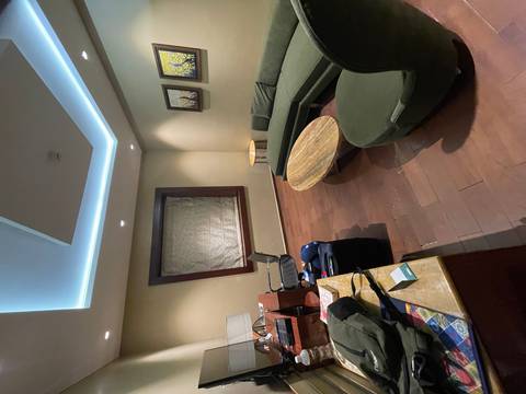       Dimly lit hotel lounge with green curved sofa, marble coffee table and travel luggage in the corner.
  