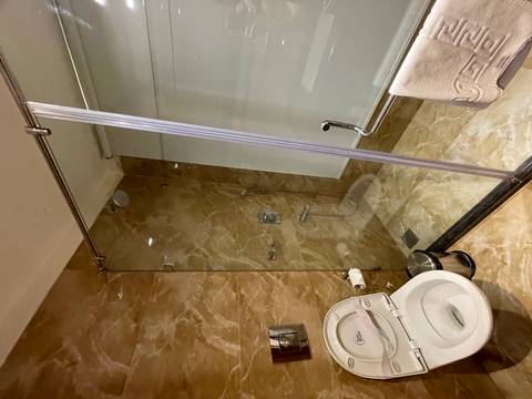       Clean hotel bathroom featuring glass-enclosed shower, marble tiles and modern fixtures.
  