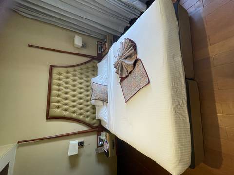       Neatly made hotel bed with decorative patterned linens arranged atop crisp white sheets.
  